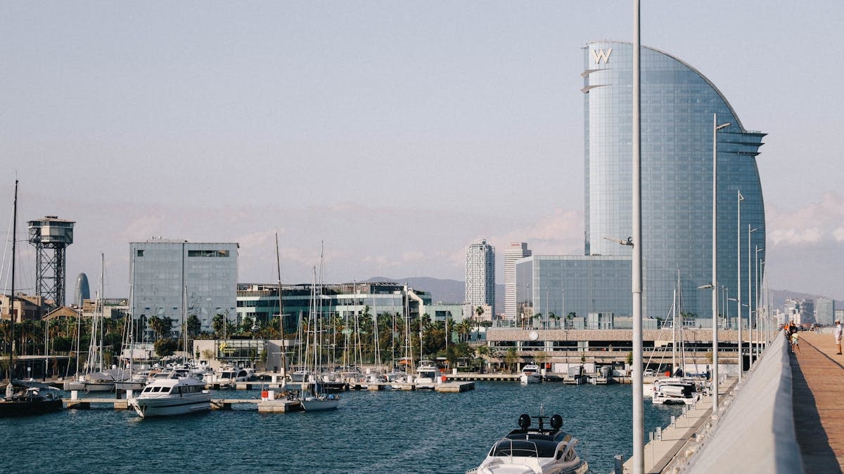 Modern architecture and boats in Barcelona's scenic harbor, with iconic skyline views.